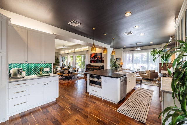 kitchen with a center island with sink, ceiling fan, dark hardwood / wood-style floors, and stainless steel appliances