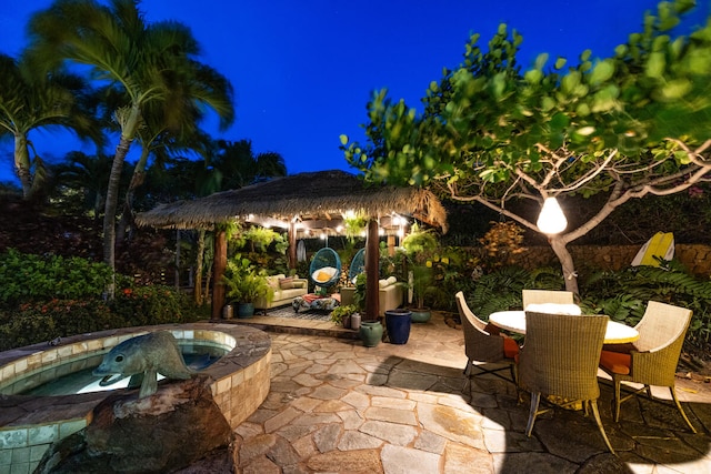 patio at twilight featuring an in ground hot tub and a gazebo