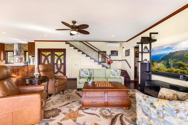 living room with a wall unit AC, ceiling fan, light hardwood / wood-style floors, and ornamental molding