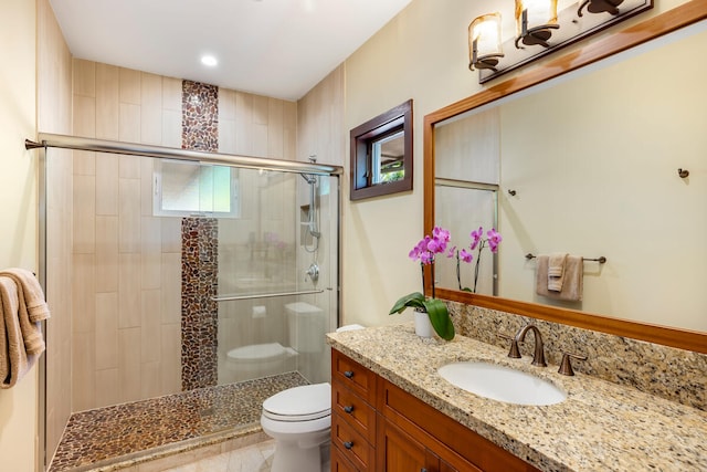 bathroom featuring vanity, an enclosed shower, and toilet