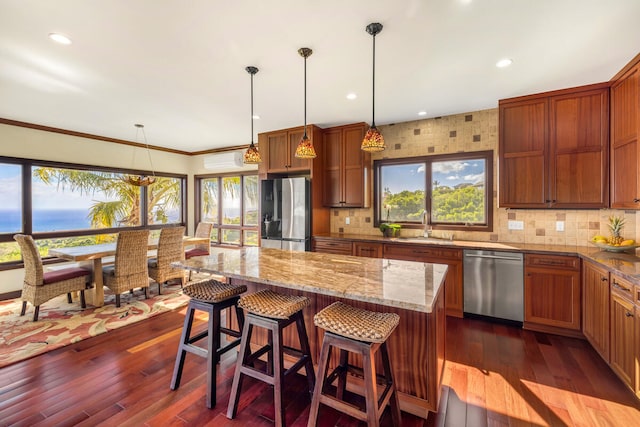 kitchen with hanging light fixtures, dark hardwood / wood-style floors, an AC wall unit, a kitchen island, and appliances with stainless steel finishes