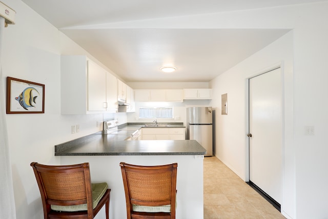 kitchen featuring white range with electric cooktop, kitchen peninsula, white cabinetry, a breakfast bar area, and stainless steel refrigerator