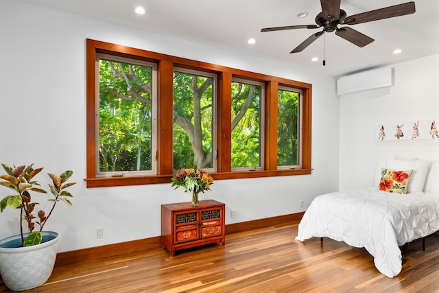 bedroom featuring ceiling fan, wood-type flooring, and an AC wall unit