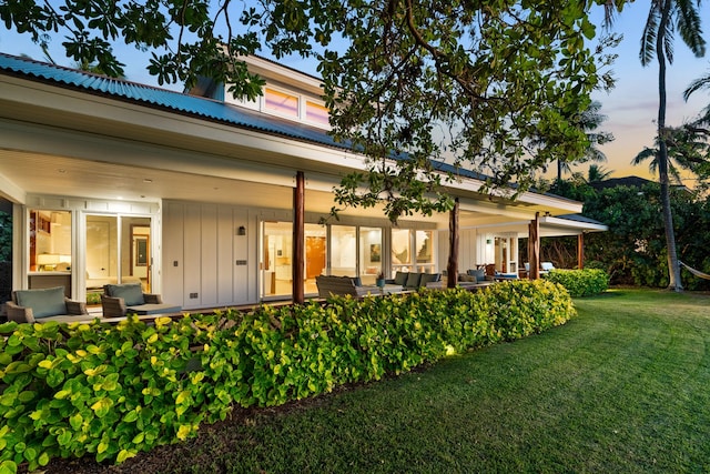 back house at dusk with an outdoor hangout area and a yard