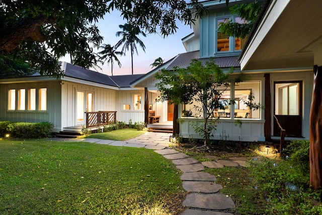 exterior entry at dusk with a porch and a lawn