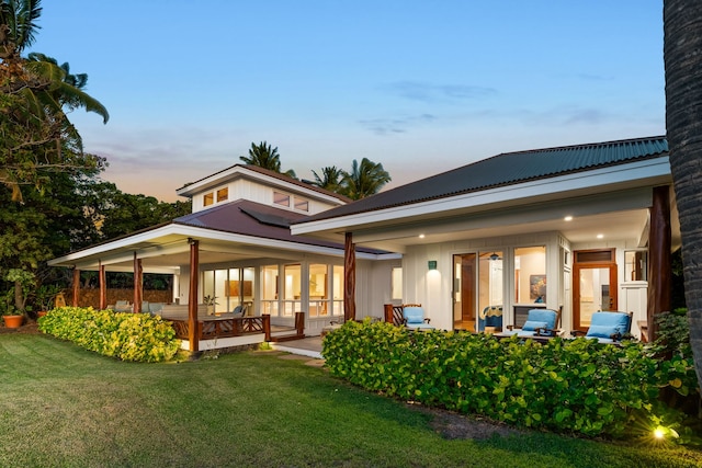 back house at dusk with a lawn