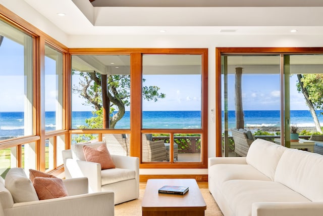 sunroom with a water view, a wealth of natural light, and a view of the beach