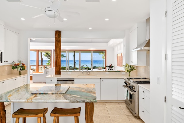 kitchen featuring a kitchen bar, appliances with stainless steel finishes, a water view, and white cabinets