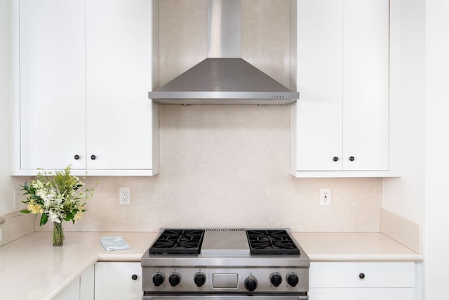 kitchen with white cabinetry, wall chimney range hood, backsplash, and stainless steel range