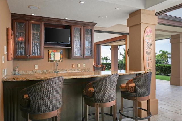 bar with light stone counters and light tile patterned floors