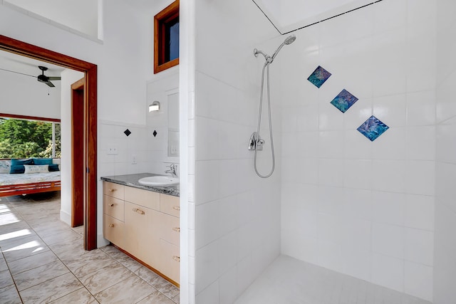 bathroom featuring vanity, ceiling fan, tiled shower, and tile walls