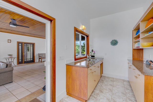 kitchen with sink, ceiling fan, light tile patterned flooring, light stone counters, and wood ceiling