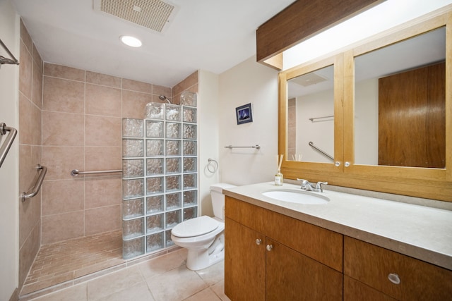 bathroom with tiled shower, vanity, tile patterned floors, and toilet