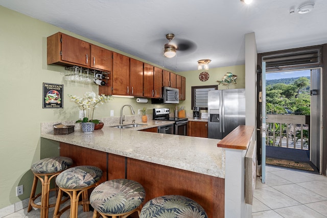 kitchen with ceiling fan, sink, kitchen peninsula, light tile patterned floors, and appliances with stainless steel finishes