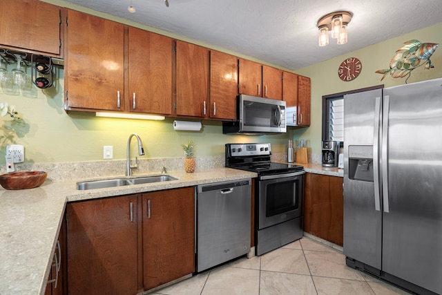 kitchen featuring a textured ceiling, light tile patterned floors, sink, and appliances with stainless steel finishes