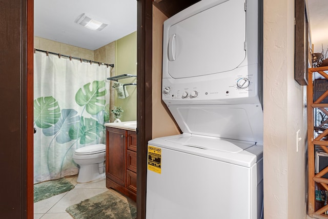 washroom with light tile patterned floors and stacked washer and dryer