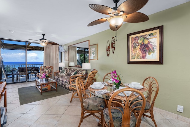 tiled dining area featuring ceiling fan and a water view