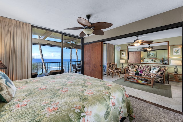 carpeted bedroom with access to exterior, ceiling fan, and a water view