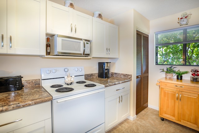 kitchen with white cabinets, white appliances, a textured ceiling, and dark stone counters