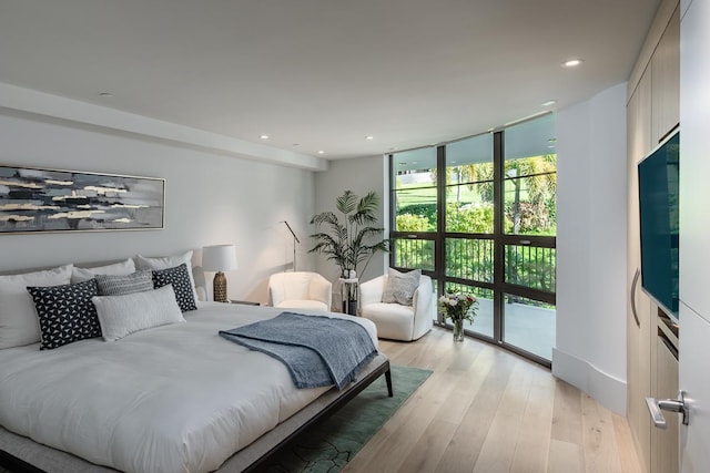 bedroom with access to outside, light hardwood / wood-style flooring, and expansive windows