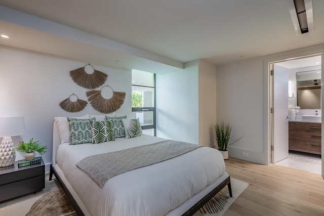 bedroom featuring ensuite bathroom and light hardwood / wood-style floors