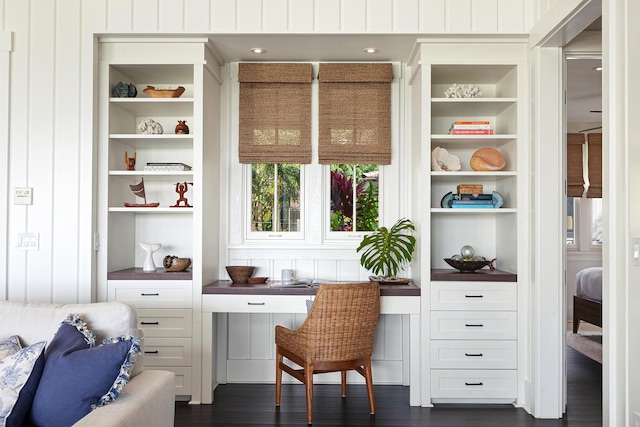 office space with built in shelves and dark hardwood / wood-style floors