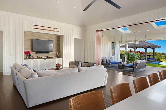 living room with ceiling fan, a healthy amount of sunlight, dark wood-type flooring, and high vaulted ceiling