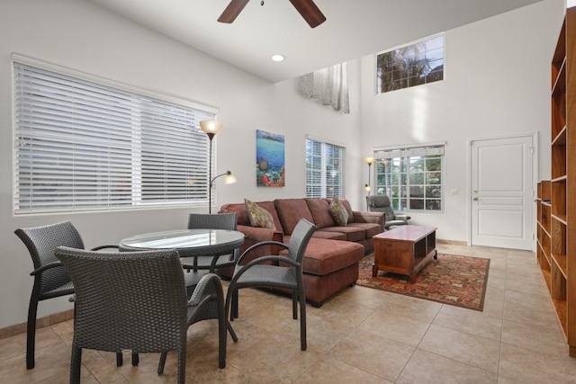 tiled living room with ceiling fan and a towering ceiling