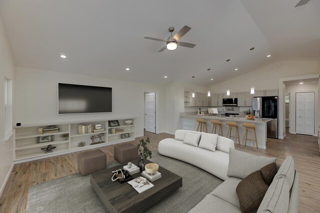 living room with ceiling fan, light wood-type flooring, sink, and vaulted ceiling