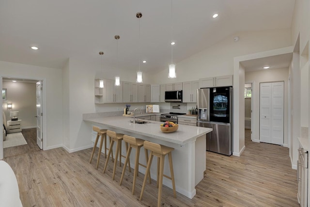 kitchen with pendant lighting, sink, vaulted ceiling, kitchen peninsula, and stainless steel appliances