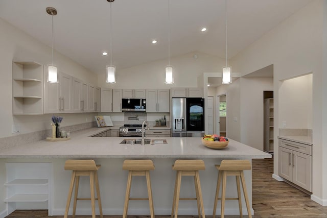 kitchen featuring sink, stainless steel appliances, kitchen peninsula, lofted ceiling, and a breakfast bar area