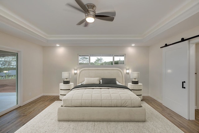 bedroom with ceiling fan, a barn door, access to exterior, and wood-type flooring