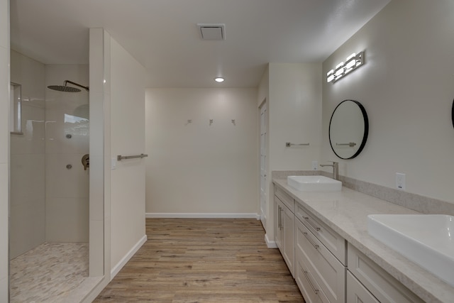 bathroom with a tile shower, vanity, and hardwood / wood-style flooring