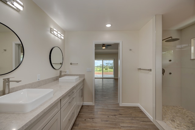 bathroom with a tile shower, ceiling fan, vanity, and hardwood / wood-style flooring