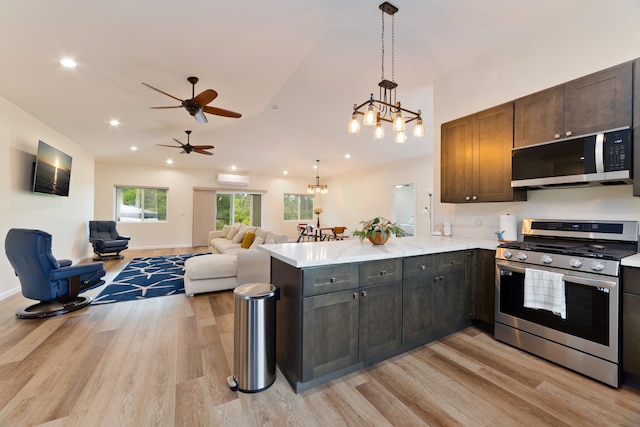 kitchen featuring dark brown cabinetry, hanging light fixtures, kitchen peninsula, appliances with stainless steel finishes, and light wood-type flooring