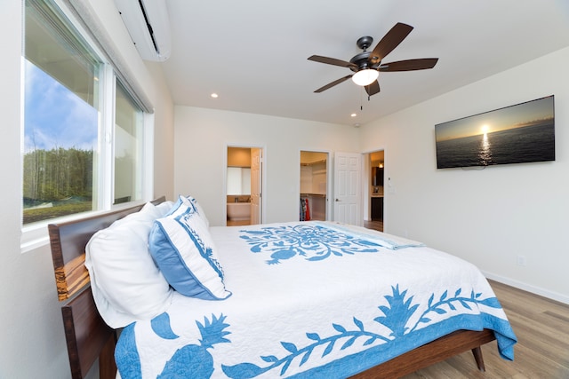 bedroom featuring multiple windows, wood-type flooring, ensuite bath, and ceiling fan