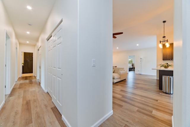 hallway with a chandelier and light hardwood / wood-style floors