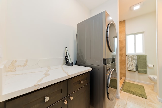 washroom with light tile patterned flooring and stacked washing maching and dryer