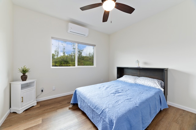 bedroom with hardwood / wood-style flooring, ceiling fan, and an AC wall unit