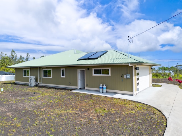 view of front facade featuring solar panels, a garage, and ac unit