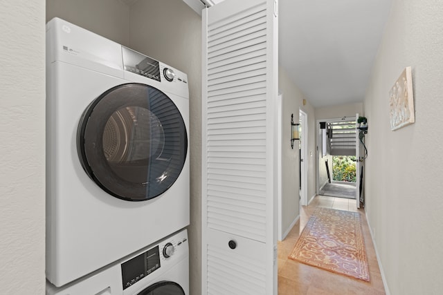 laundry area featuring light tile patterned floors and stacked washer / dryer