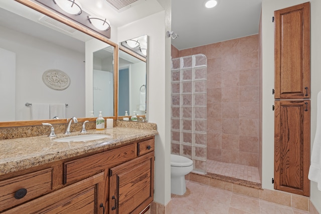 bathroom featuring toilet, a tile shower, vanity, and tile patterned floors