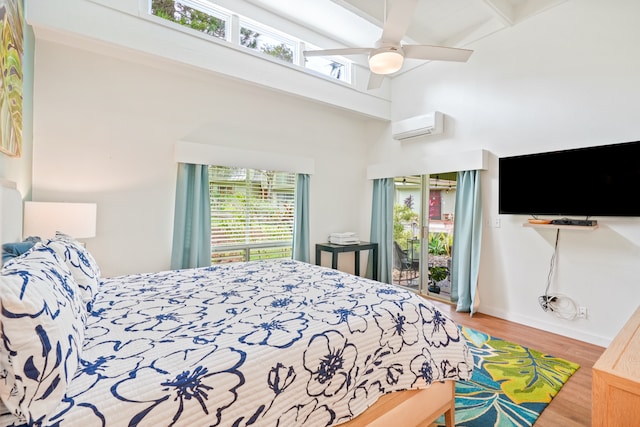 bedroom with a high ceiling, a wall unit AC, ceiling fan, hardwood / wood-style floors, and access to outside