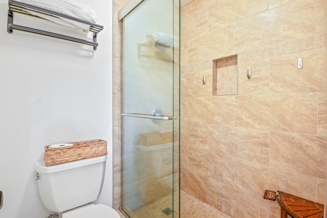 bathroom featuring toilet and a shower with shower door