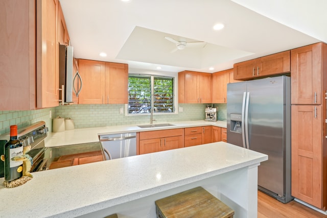 kitchen with kitchen peninsula, stainless steel appliances, sink, and a breakfast bar