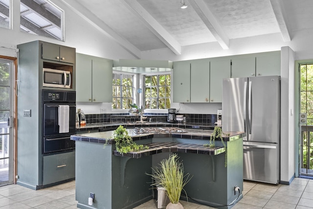 kitchen featuring lofted ceiling with beams, decorative backsplash, light tile patterned floors, tile counters, and stainless steel appliances