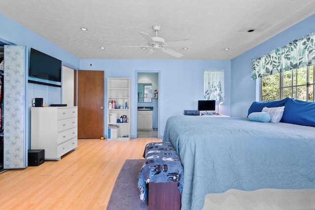 bedroom featuring light wood-type flooring, ensuite bathroom, and ceiling fan