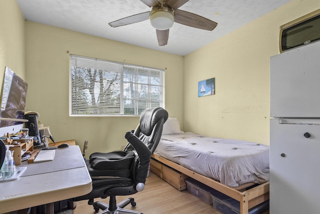 bedroom featuring ceiling fan, white refrigerator, and light hardwood / wood-style flooring