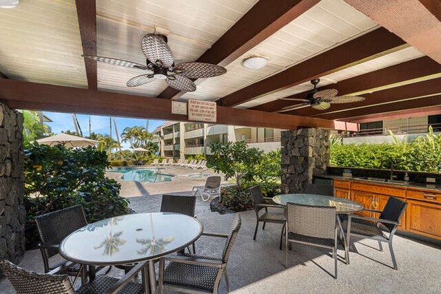 view of patio with ceiling fan, sink, and a community pool