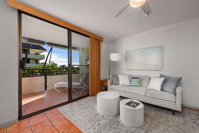 living room featuring tile patterned flooring, a textured ceiling, expansive windows, and ceiling fan